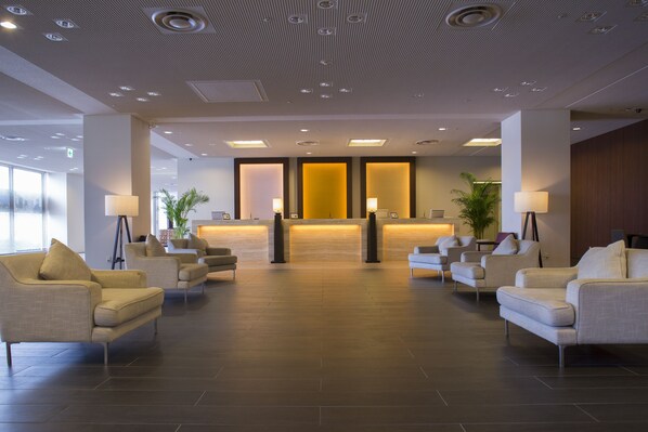 Un hall d’entrée moderne avec un comptoir d’accueil, un espace salon et un plafond orné de motifs.