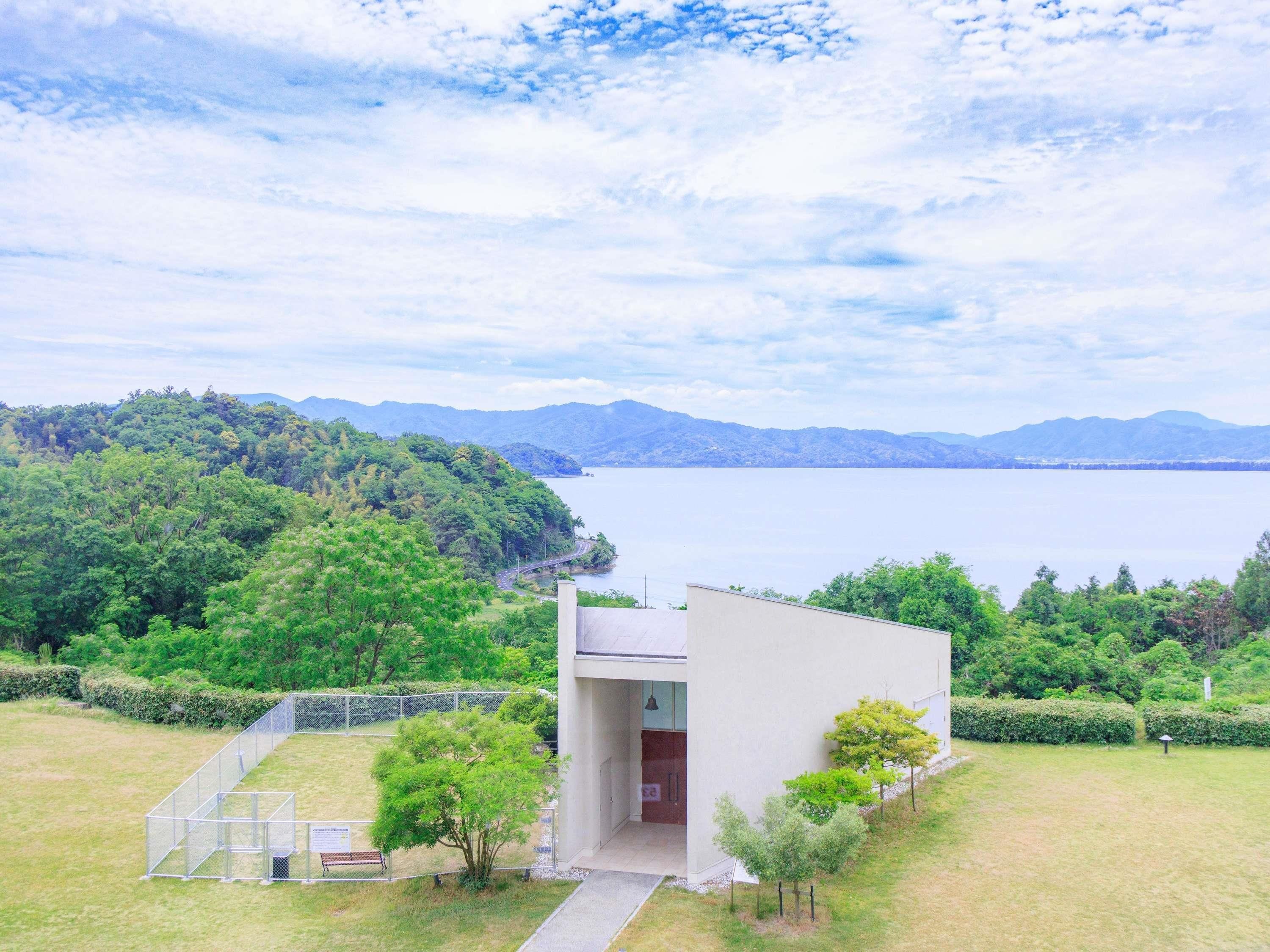 A modern building with a flat roof, surrounded by a well-maintained lawn and a metal fence.