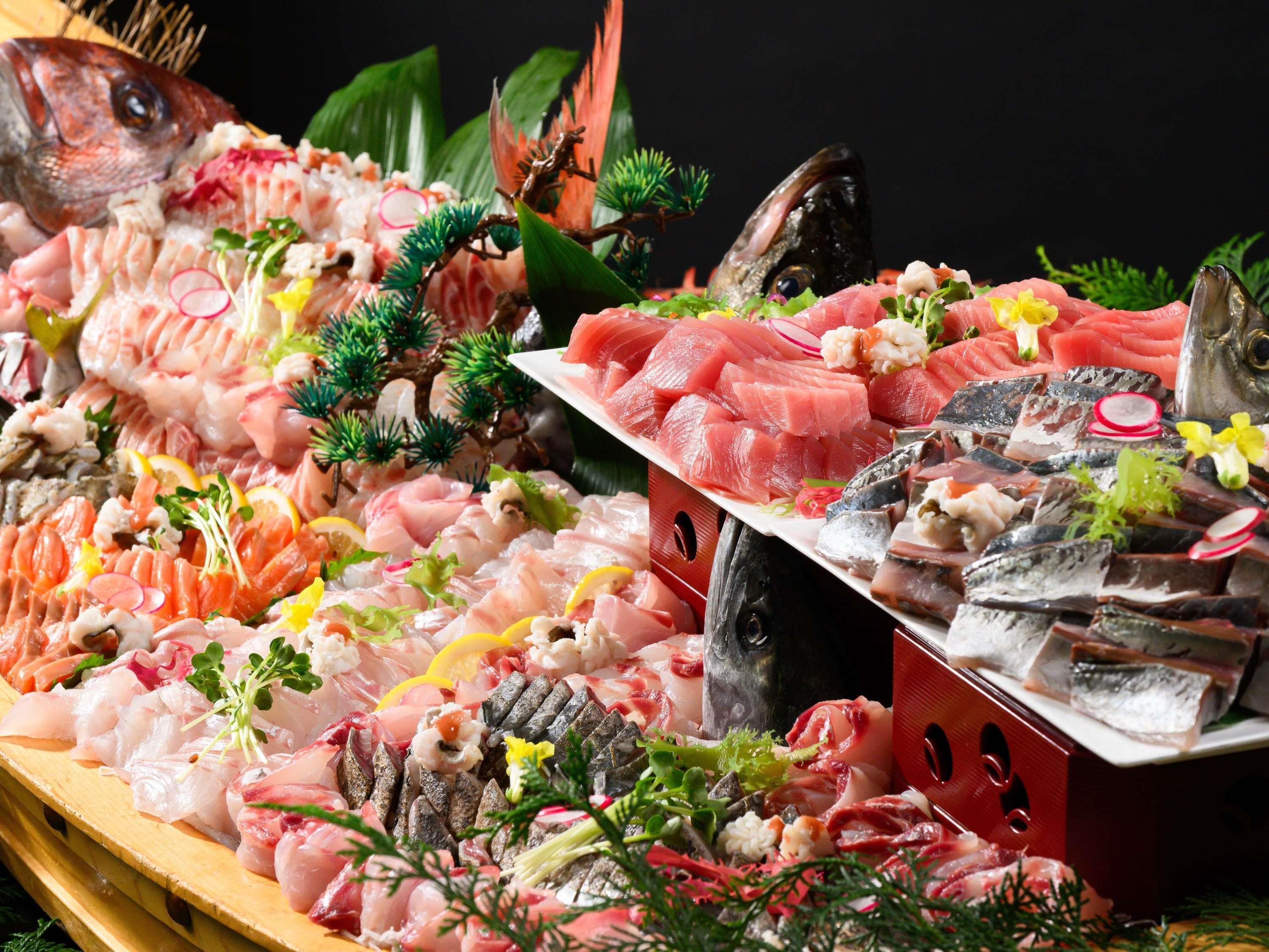 Eine Auswahl frischer Meeresfrüchte auf Eis, darunter Fisch und Schalentiere, mit dekorativem Grün und Blumen.