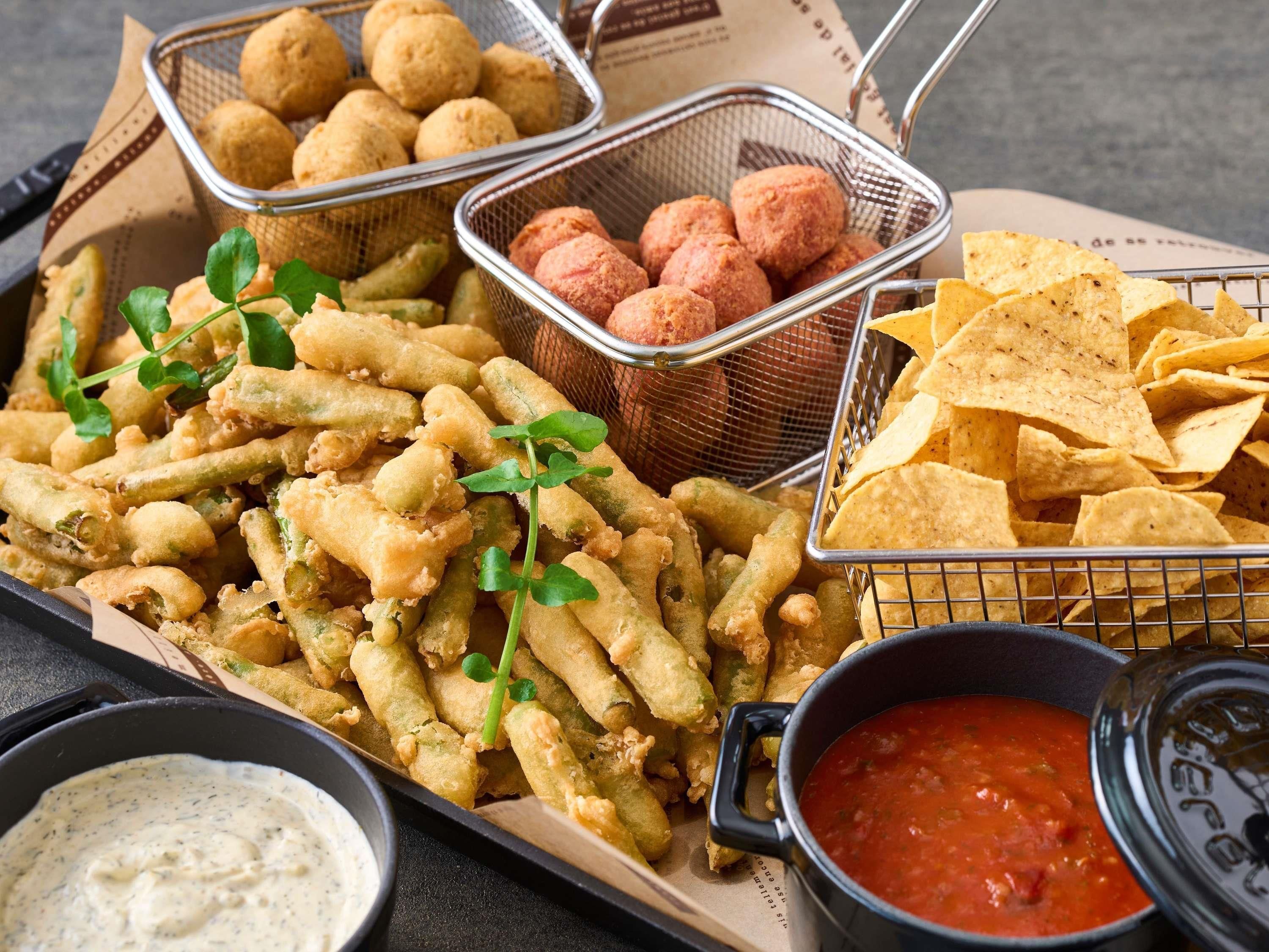A tray of fried food including calamari, fritters, and chips, with dipping sauces.