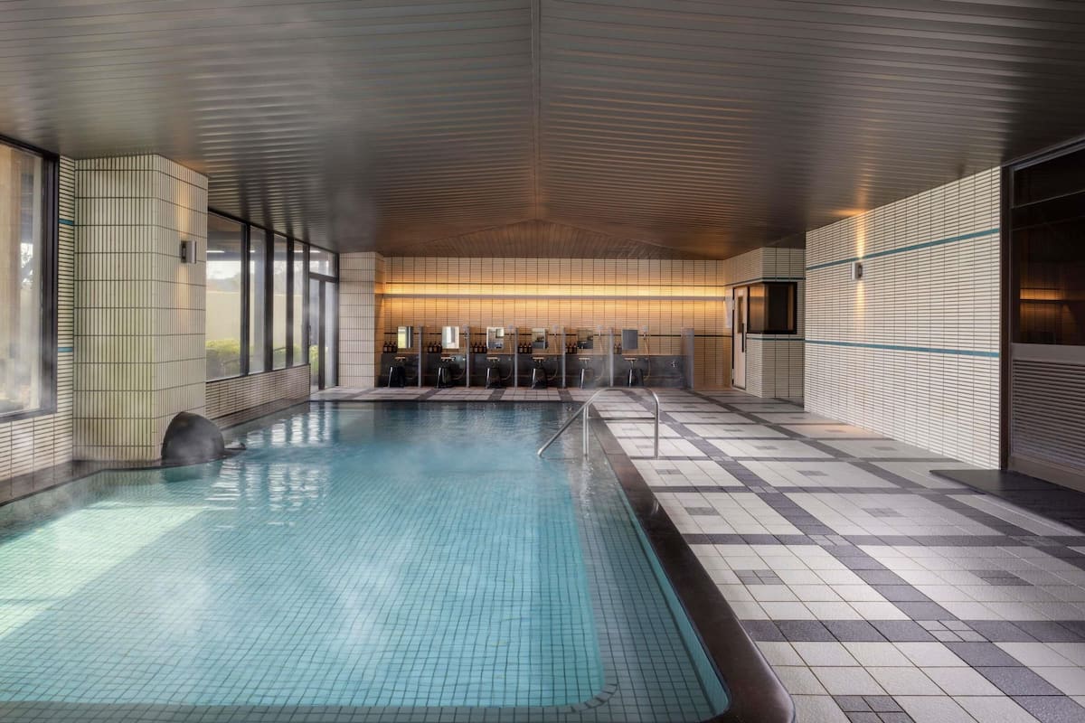 A modern indoor pool with tiled walls and a wooden ceiling.