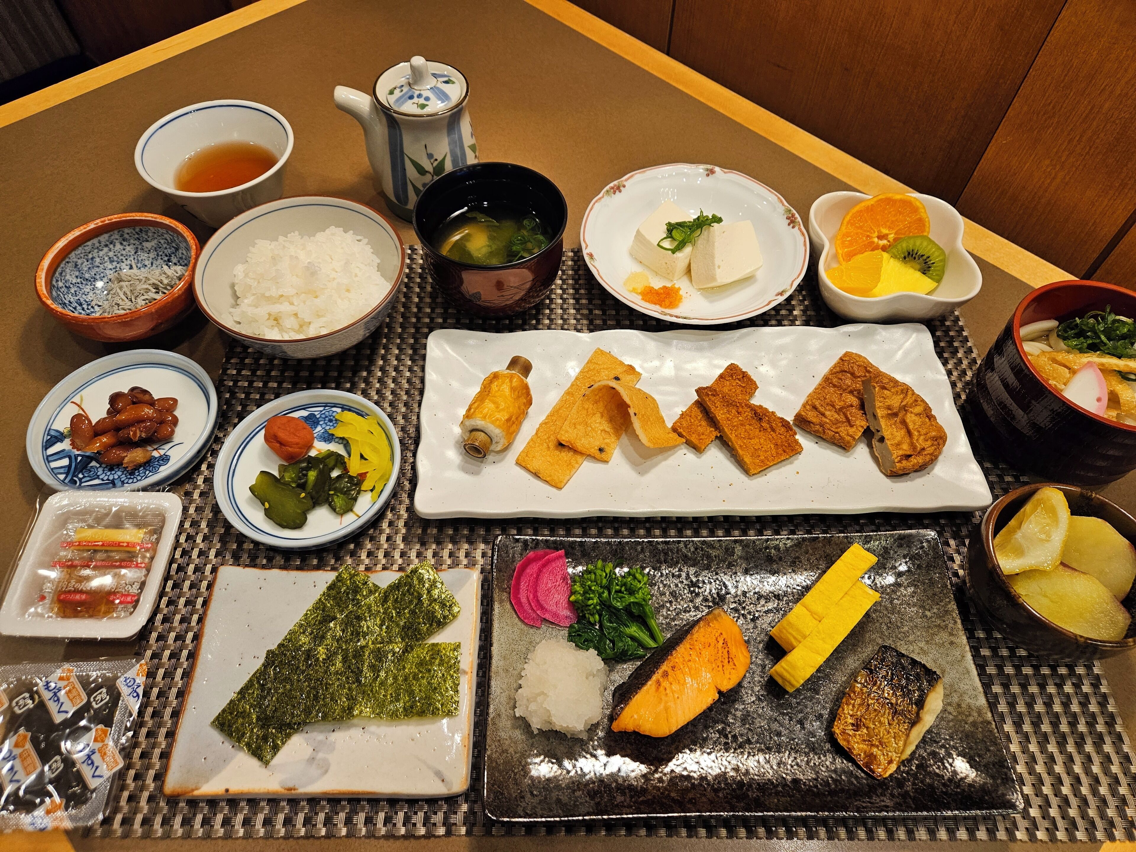 Een traditionele Japanse maaltijdopstelling met diverse gerechten, waaronder sushi, tempura en ingelegde groenten.