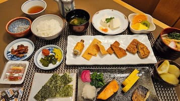 Un repas japonais traditionnel, composé de différents plats, notamment des sushis, des beignets de tempura et des légumes marinés.