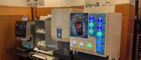 Una máquina de café y un dispensador de bebidas con varias opciones, incluyendo Pepsi.