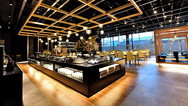 A modern cafe with a central island counter, seating area, and large windows. - Tsukino Hotel (Sakata)