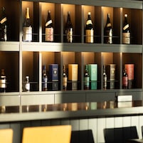 Zona de bar con estantes llenos de botellas de licores y cajas.