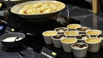 A dining table with a variety of dishes, including a bowl of soup, a plate of food, and several cups of a beverage.