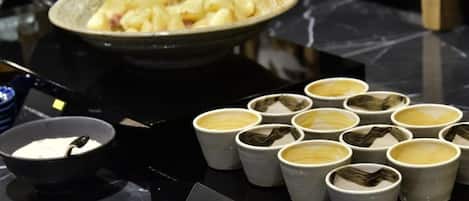 Une table à manger dressée avec une variété de plats, notamment un bol de soupe, une assiette de nourriture et plusieurs tasses d’une boisson.
