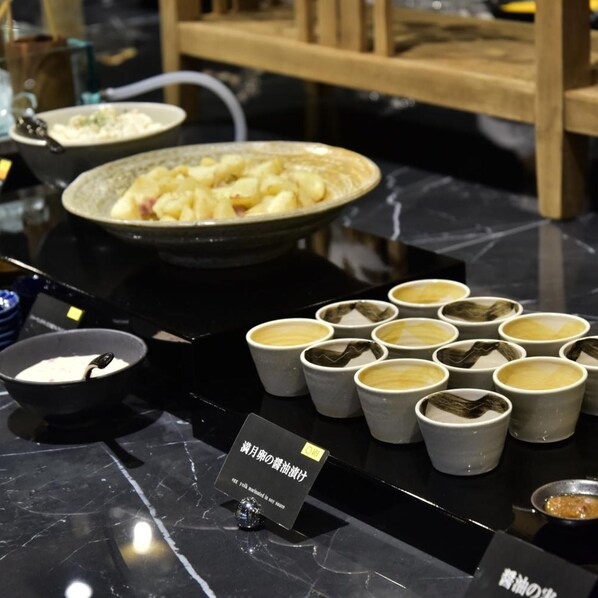 A dining table with a variety of dishes, including a bowl of soup, a plate of food, and several cups of a beverage. - Tsukino Hotel (Sakata)