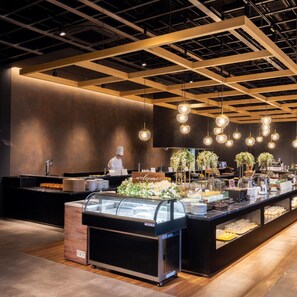 A modern buffet setup with a chef preparing food, a welcome sign, and a variety of food items displayed. - Tsukino Hotel (Sakata)
