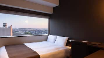 Une chambre d’hôtel avec une grande fenêtre, un lit, un bureau et une chaise.