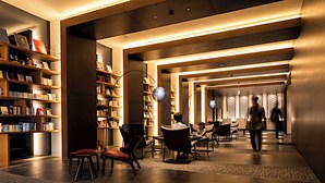 A modern lobby with bookshelves, seating areas, and a well-lit corridor. - Tsukino Hotel (Sakata)