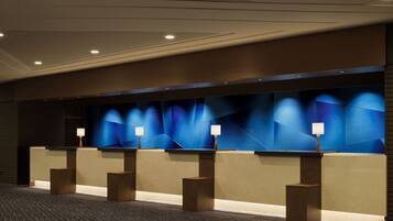 A reception area with a modern design, featuring a long counter with multiple lamps and a geometric wall design.