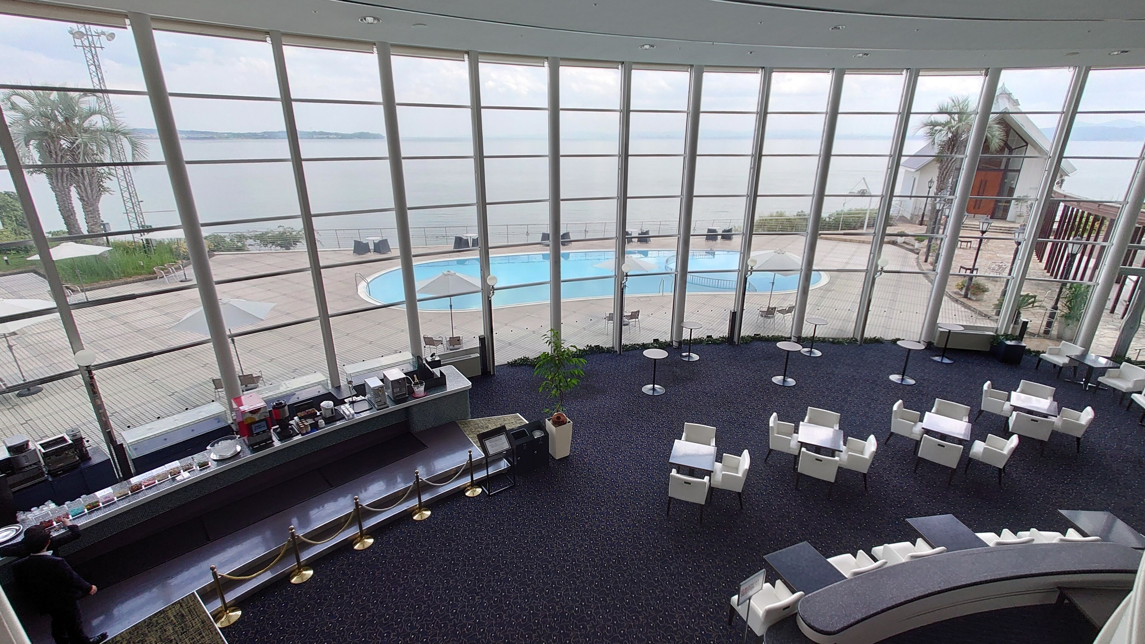 A poolside area with a view of the sea, a bar, and outdoor seating.
