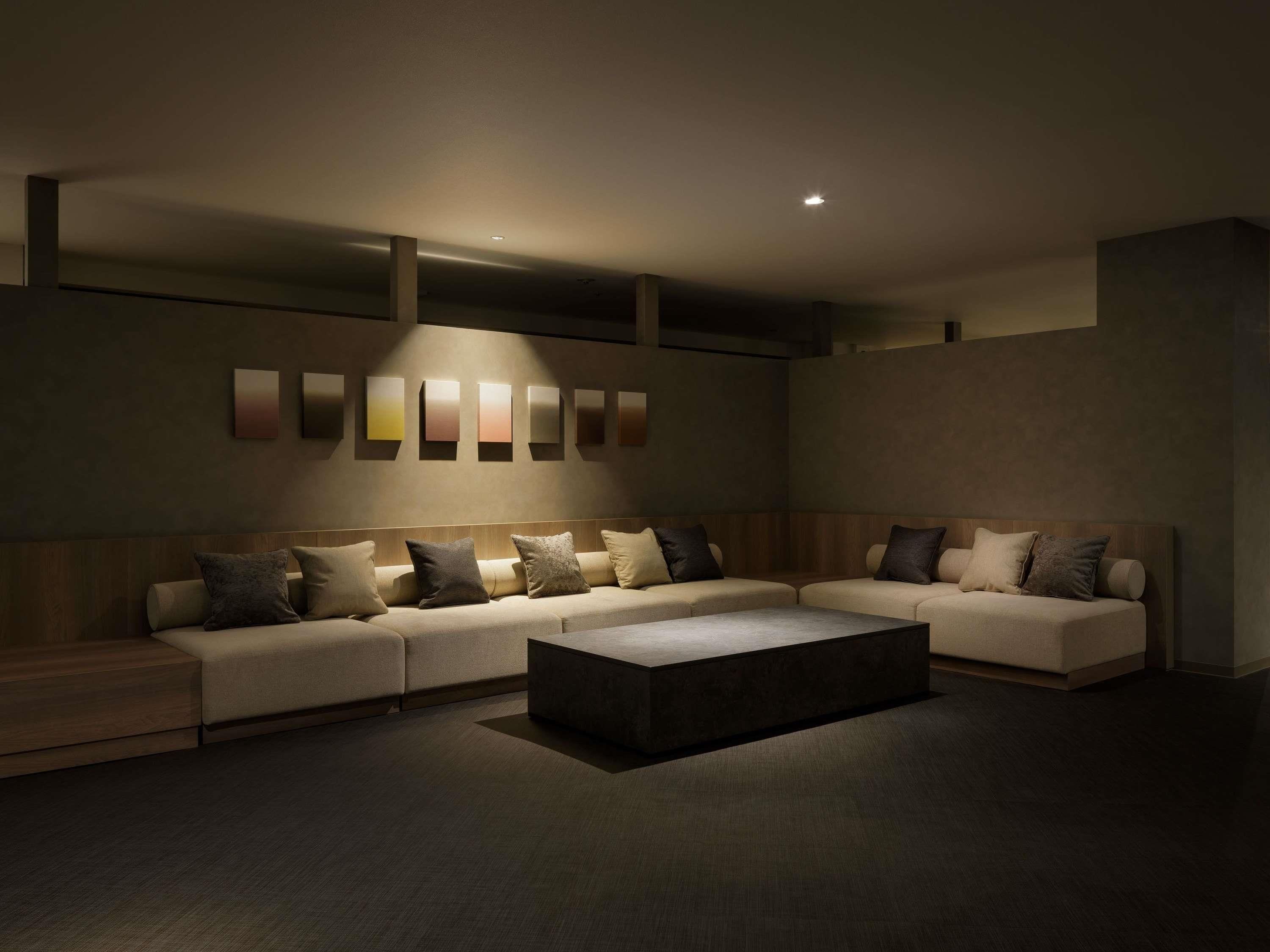 Una sala moderna con un sofá modular, una mesa de centro e iluminación en la pared.