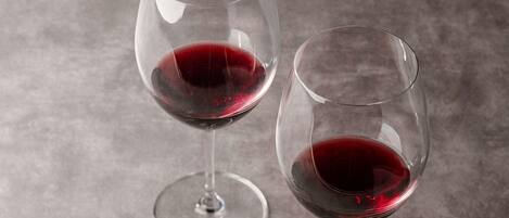 Two wine glasses with red liquid on a textured surface.