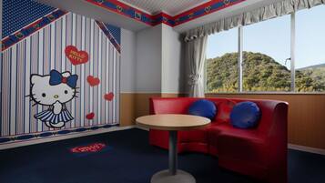 A room with a red sofa, a round table, and a wall with Hello Kitty decorations.
