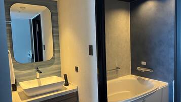 A modern bathroom with a large bathtub, a sink with a mirror, and a shower area.