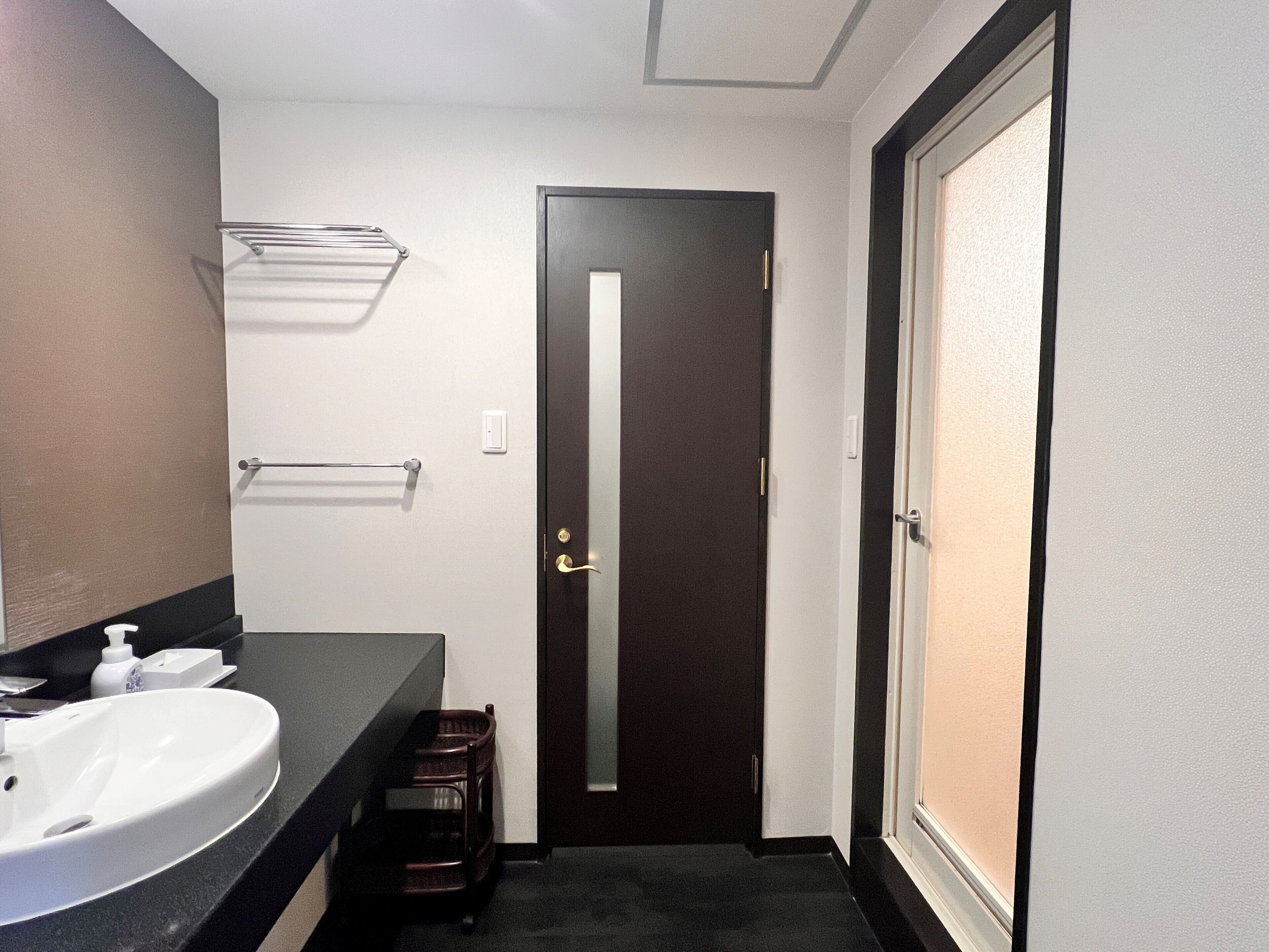 A bathroom with a white sink, a mirror, a towel rack, and a door.