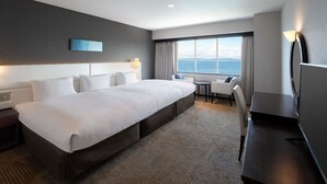Habitación de hotel moderna con una cama grande, un escritorio y vistas al mar.