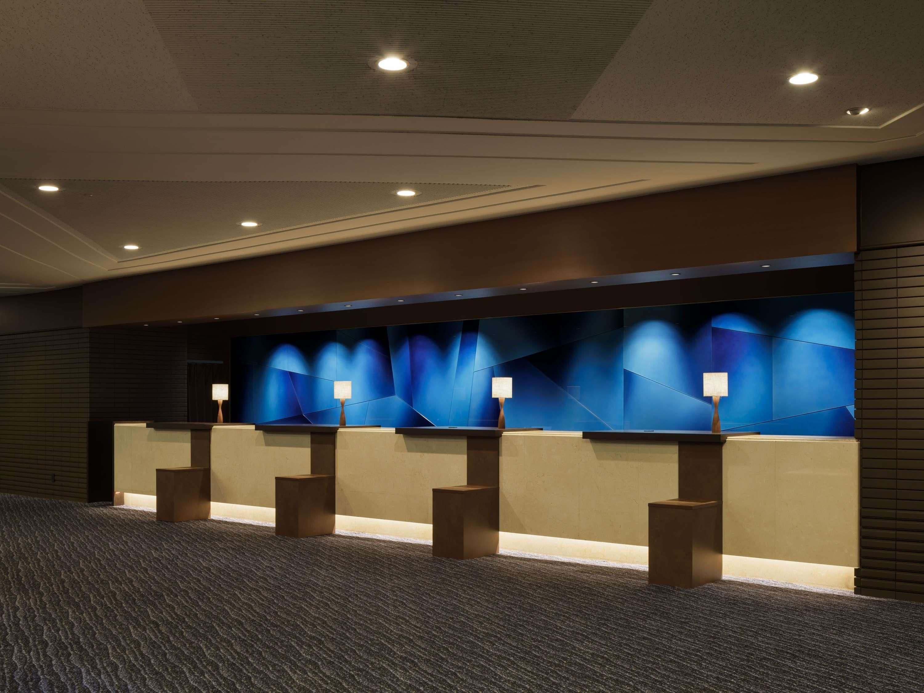 A reception area with a modern design, featuring a long counter with multiple light fixtures and a patterned carpet.