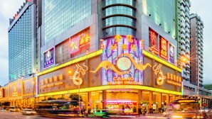 A multi-story hotel with a prominent casino sign on the ground floor, featuring a golden dragon emblem. - Hotel Golden Dragon (Macau)