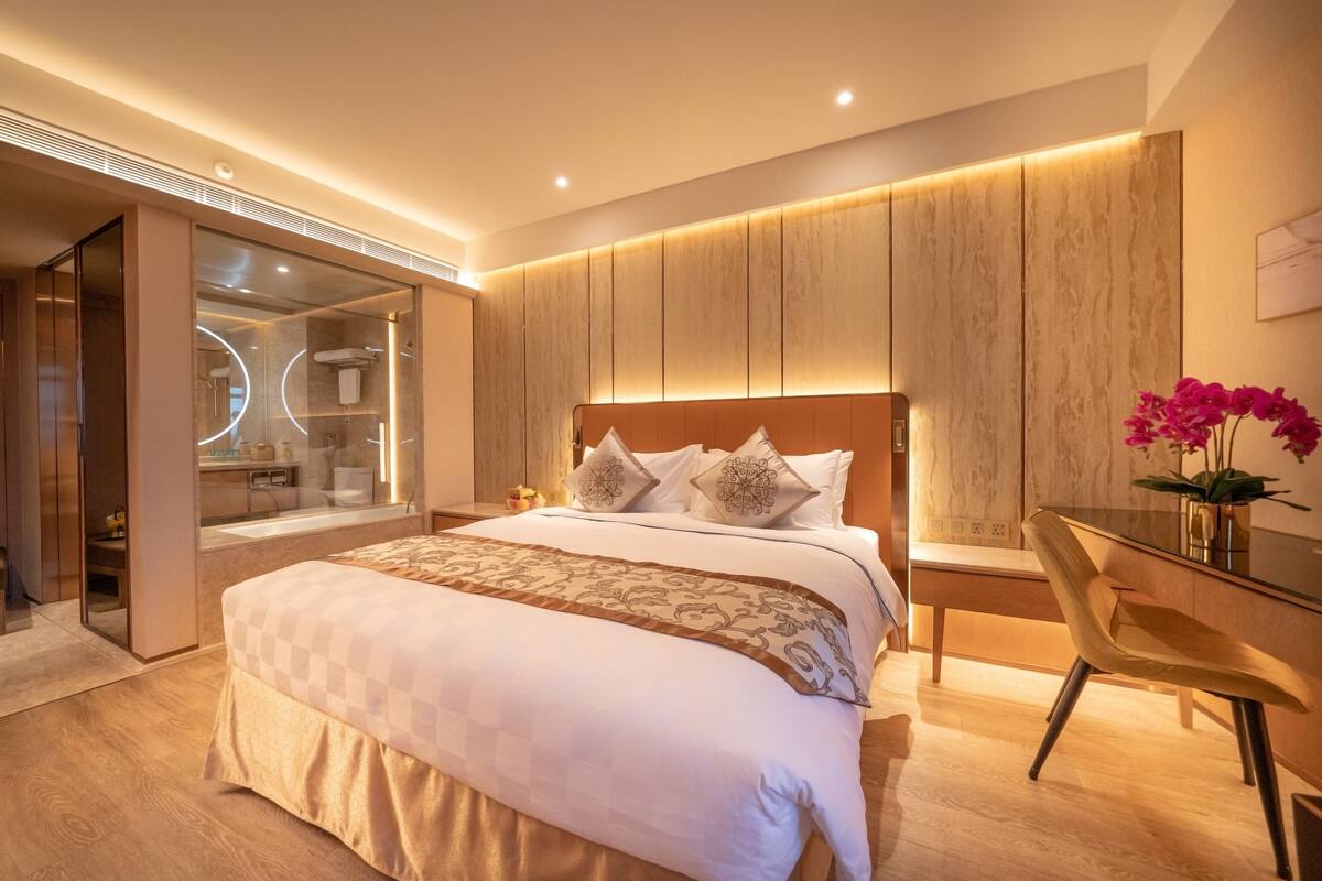 A modern bedroom with a large bed, a desk, and a chair.