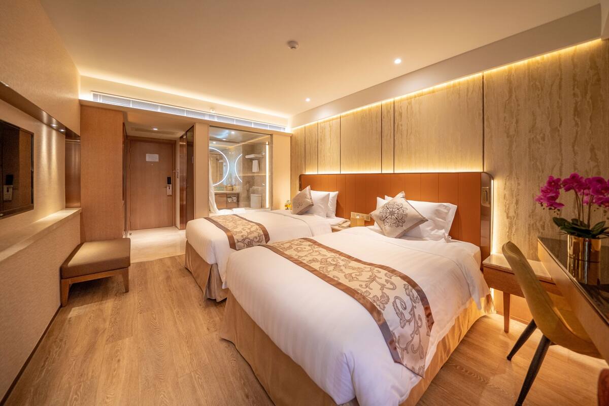 A modern hotel room with two beds, a desk, and a vanity.