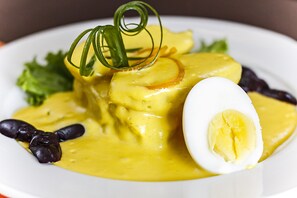 A plate of food with a boiled egg, yellow sauce, and black olives. - Intiotel - Chiclayo (Chiclayo)