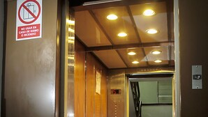 An elevator interior with wooden paneling, a digital display, and a sign prohibiting the use of the elevator in case of fire or smoke. - Intiotel - Chiclayo (Chiclayo)