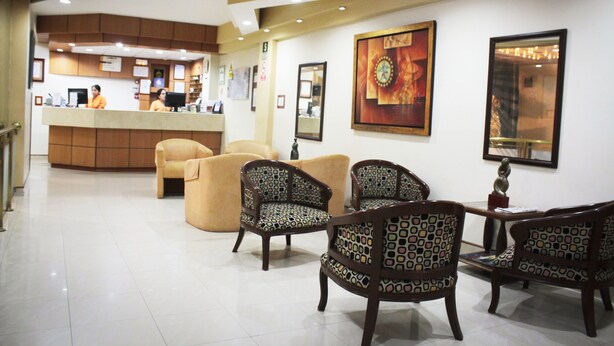 A hotel lobby with a reception desk, patterned chairs, and artwork on the walls. - Intiotel - Chiclayo (Chiclayo)
