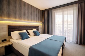 A double bed with a wooden headboard and two pillows, a nightstand, and a large window with curtains. - Hotel Haliaetum San Simon Resort (Izola)