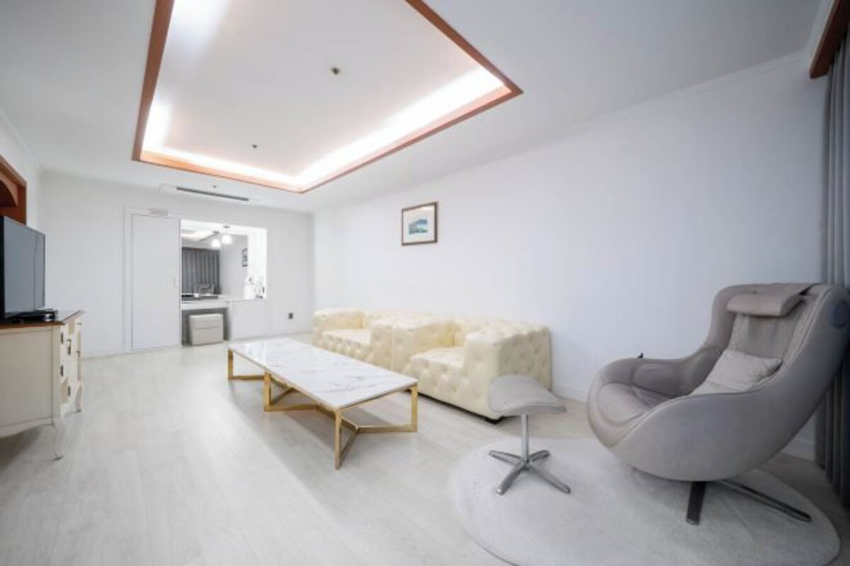 A modern living room with a sofa, a chair, a coffee table, and a television.