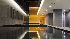 Un pasillo moderno y bien iluminado con piso reflectante, un accesorio de iluminación central y un revestimiento de pared de madera.