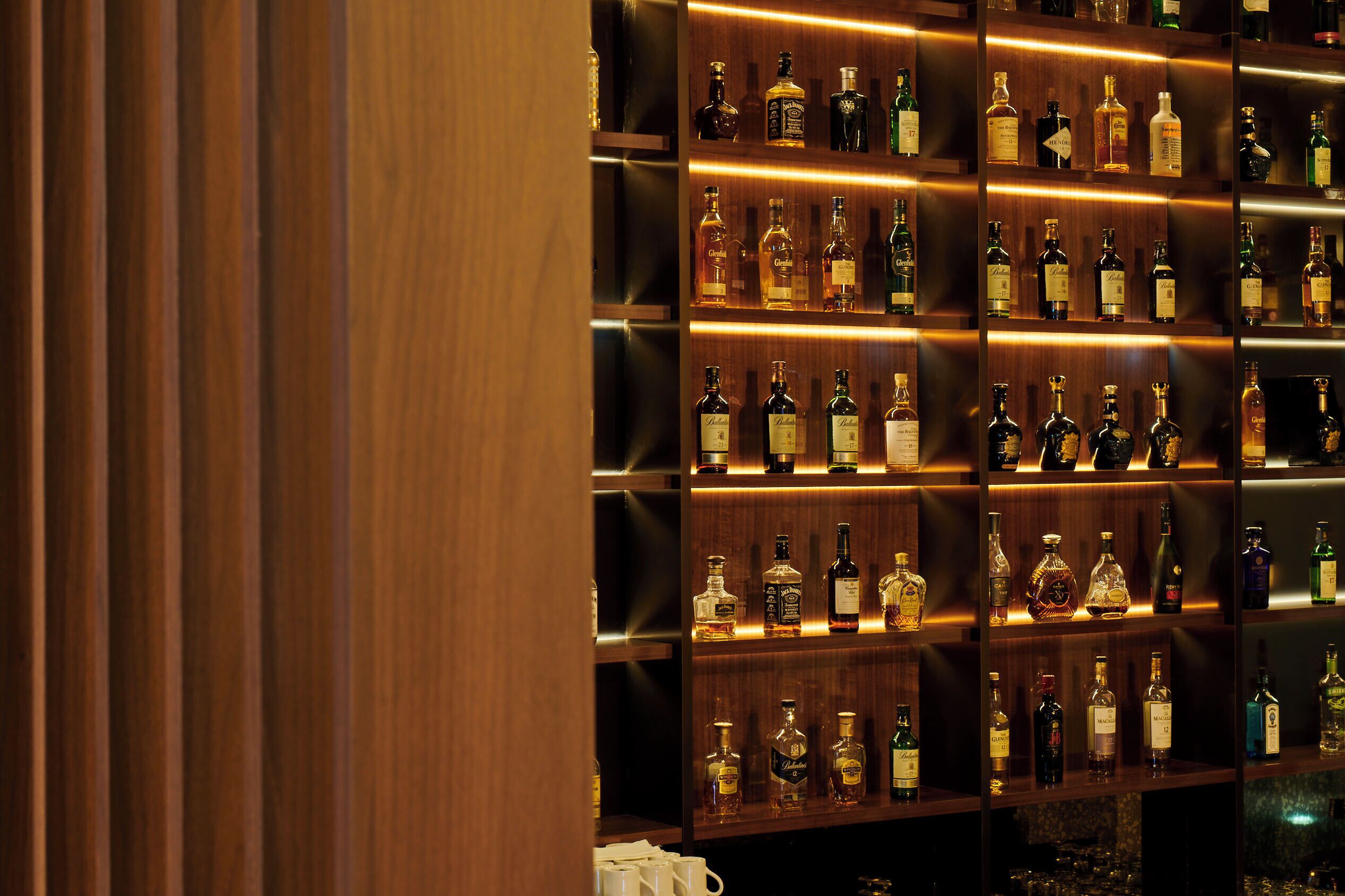 A bar area with shelves of various liquor bottles.