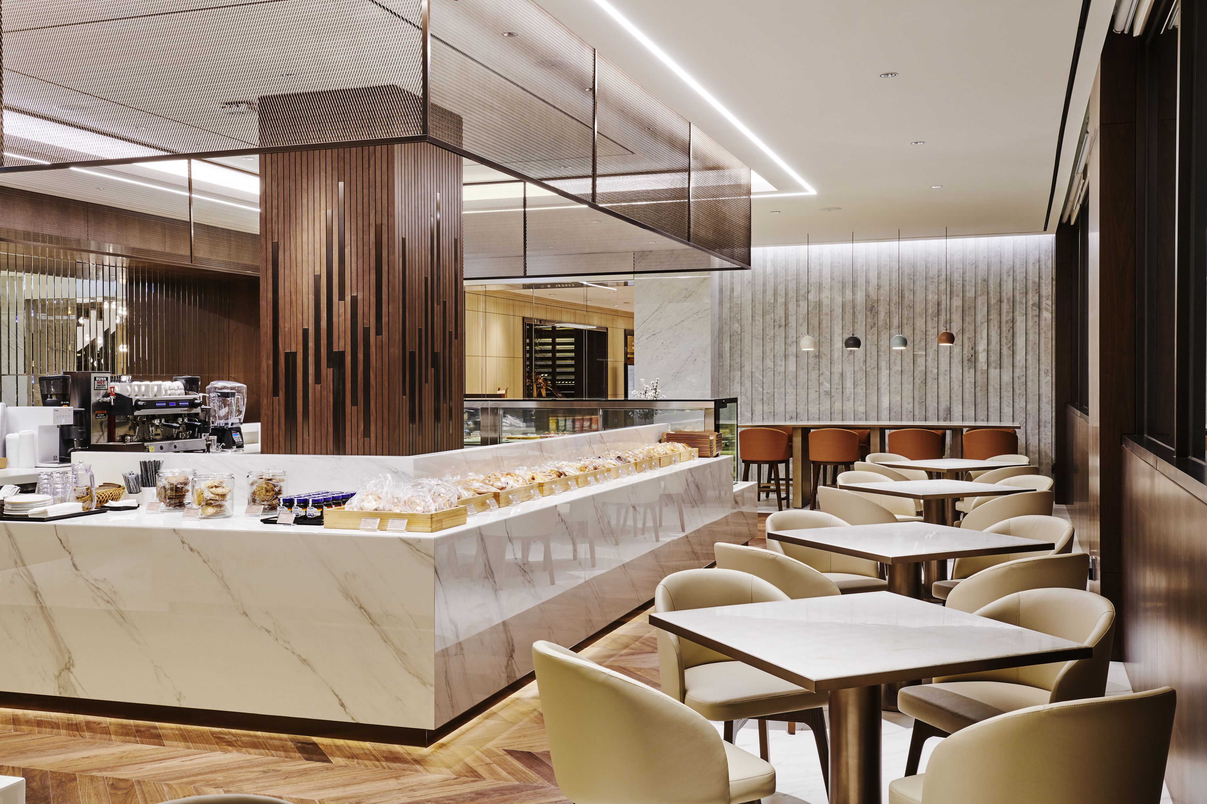 A modern cafe with a marble counter, seating area, and a coffee machine.