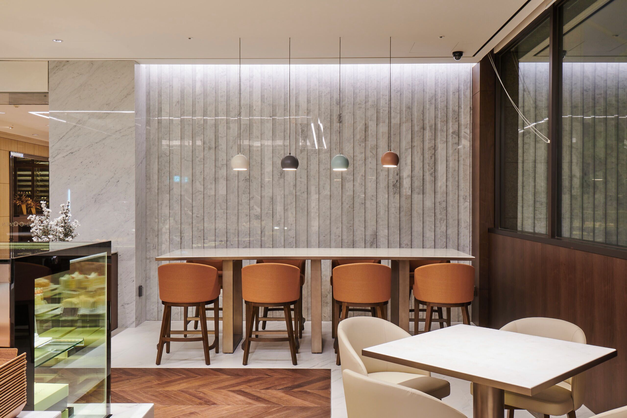 Un interior moderno con una pared de mármol, lámparas colgantes y una mesa de madera con sillas.