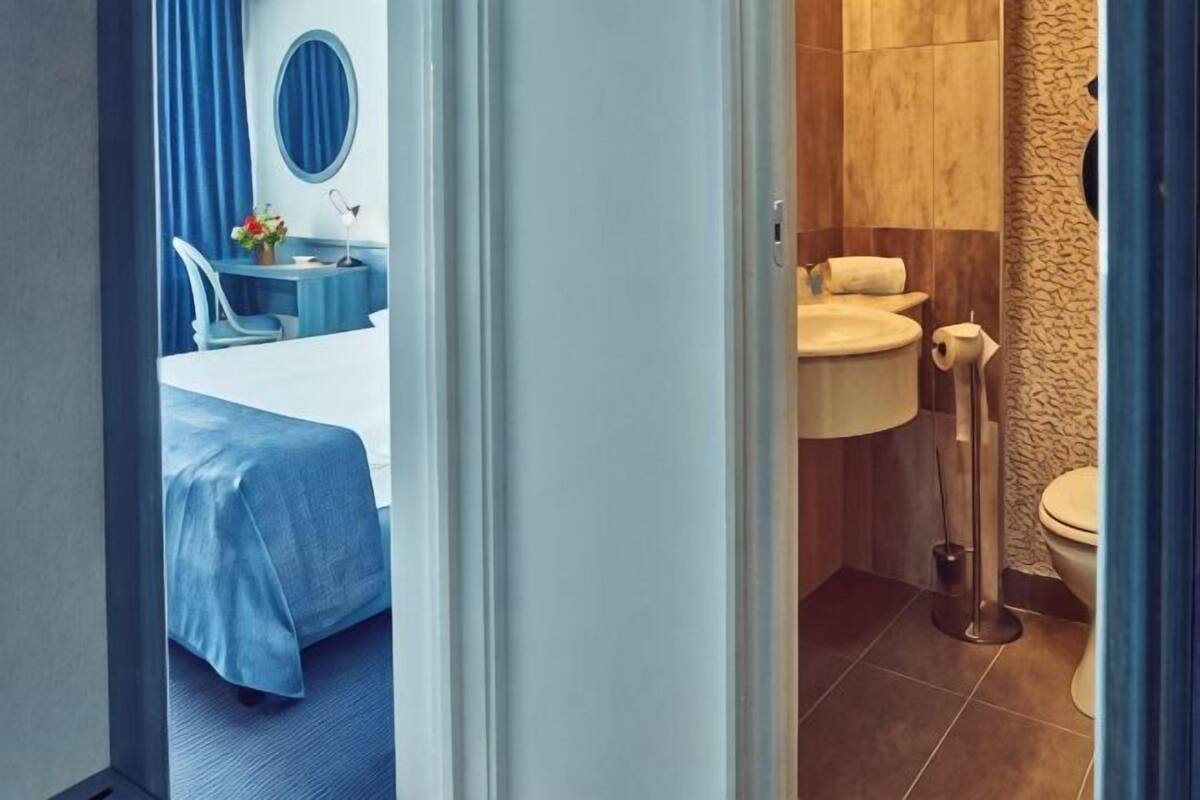 Habitación de hotel con cama, baño con inodoro y lavamanos.