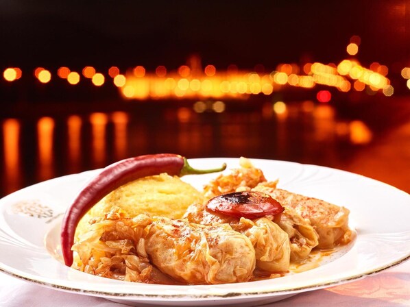 A plate of stuffed cabbage rolls with a red chili and a side of mashed potatoes.