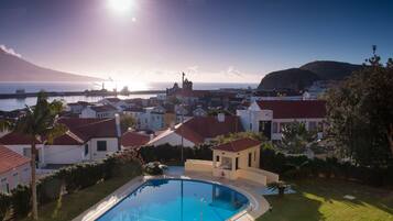 Een buitenzwembad, parasols bij het zwembad en ligstoelen