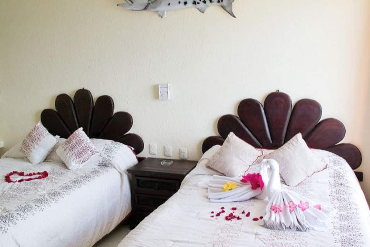 Two beds with unique headboards, a wall-mounted shark decoration, and a small bedside table with a lamp.