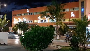 A hotel with multiple floors, palm trees, and a well-lit facade.