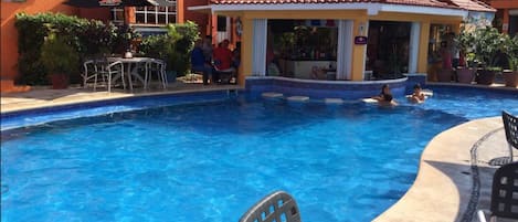 A swimming pool with lounge chairs and a covered seating area.