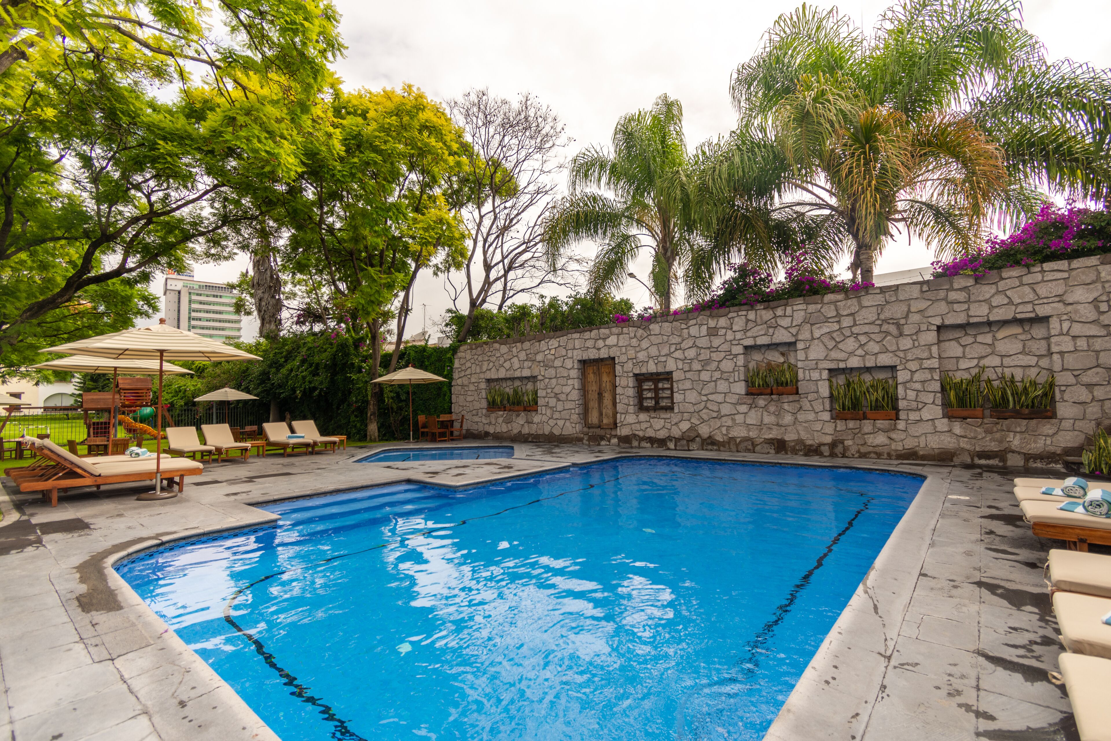 A swimming pool with lounge chairs and a stone wall.