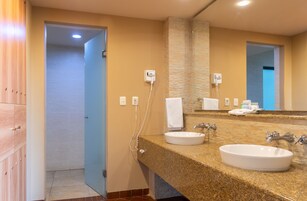 Un baño con dos lavamanos, un espejo grande y un perchero para toallas.