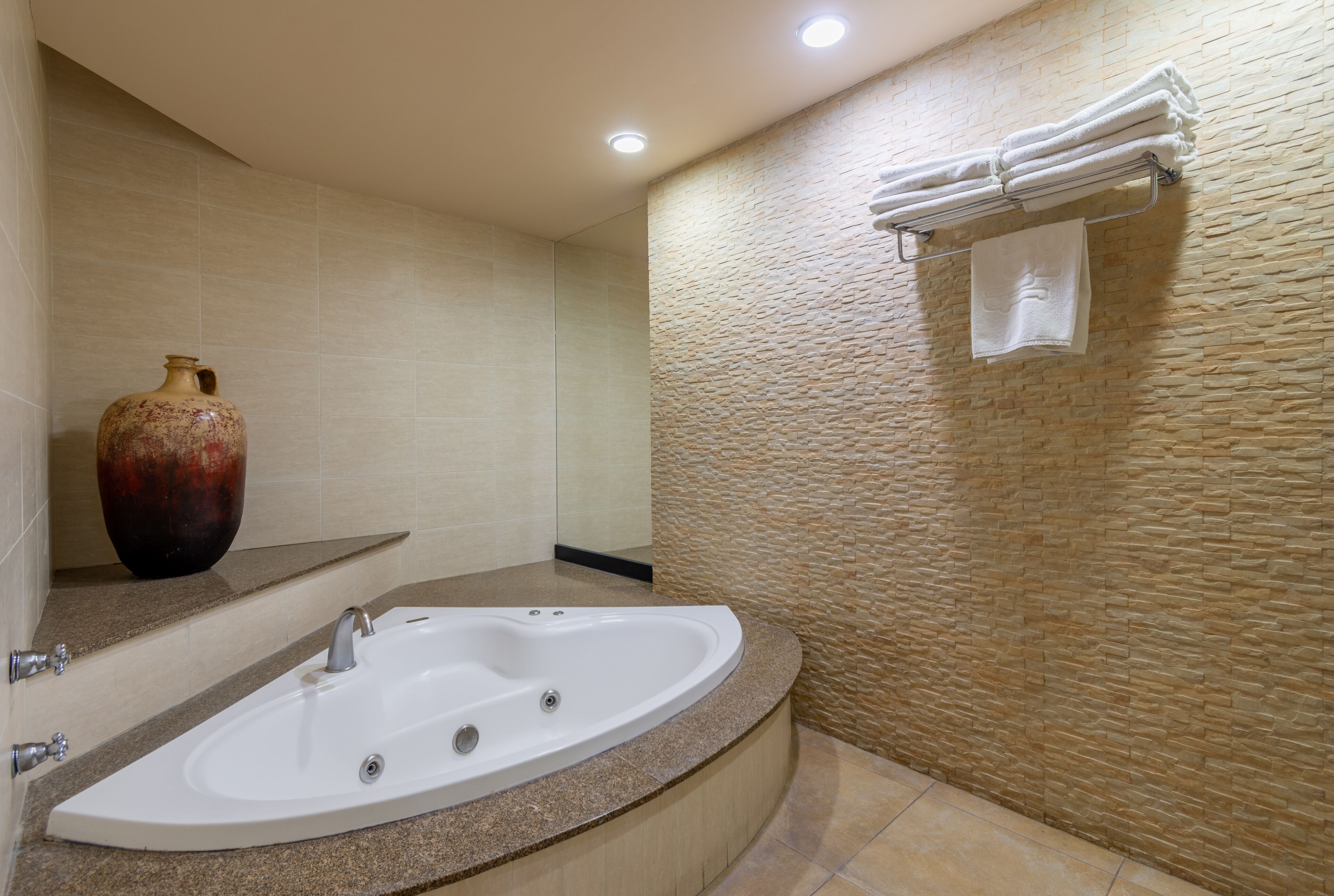 A modern bathroom with a freestanding bathtub, a large vase, and a towel rack.