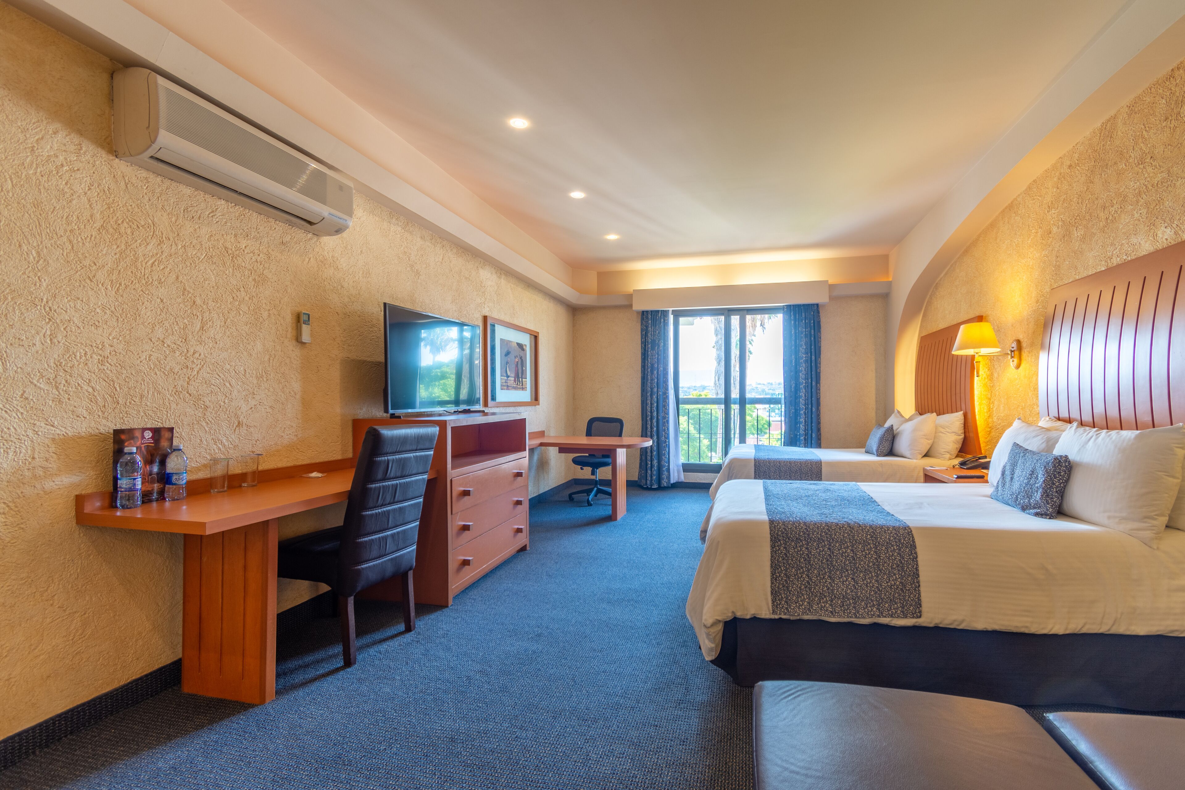 A hotel room with a bed, desk, chair, and TV.