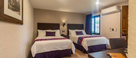 Habitación de hotel con dos camas, un escritorio y una ventana con cortinas azules.