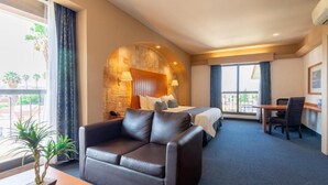 A hotel room with a bed, a sofa, a desk, and a view of the outdoors. - Hotel Flamingo Inn (Querétaro)