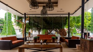 A modern indoor space with a wooden table, black sofas, and hanging pendant lights. - Hotel Flamingo Inn (Querétaro)